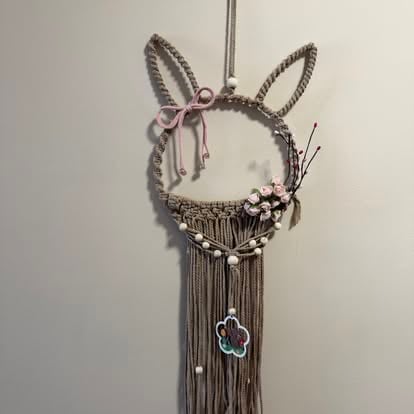 Macramé bunny head wall hanging with rope ears, pink bow, floral accents, and long fringe tassel bottom