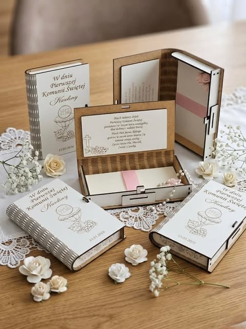 Collection of elegant wedding invitation boxes with floral designs, displayed on a wooden table with decorative white flowers and lace
