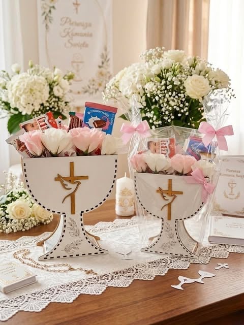 Two decorative baskets with gold crosses and pink bows filled with flowers, candles, and religious items on a wooden table with white flowers in background
