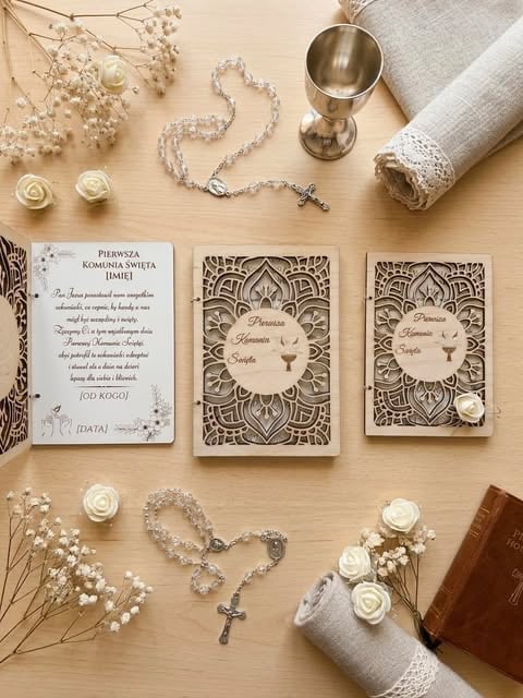 Flat lay of wedding invitations, rosaries, babys breath flowers, white roses, chalice, and religious books on beige surface